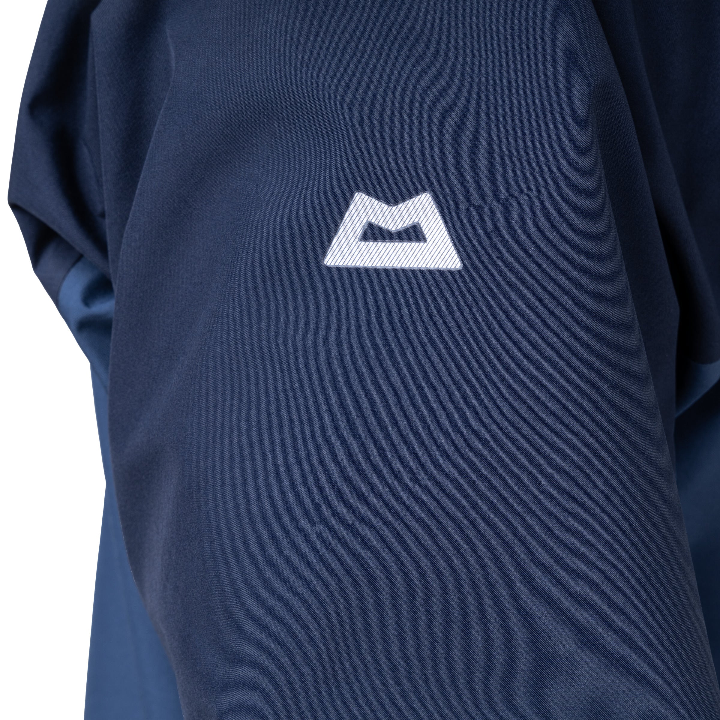 Close-up of a navy blue long-sleeve top with a white stylized mountain logo on the chest, showing the fabric texture and sleeve detail.