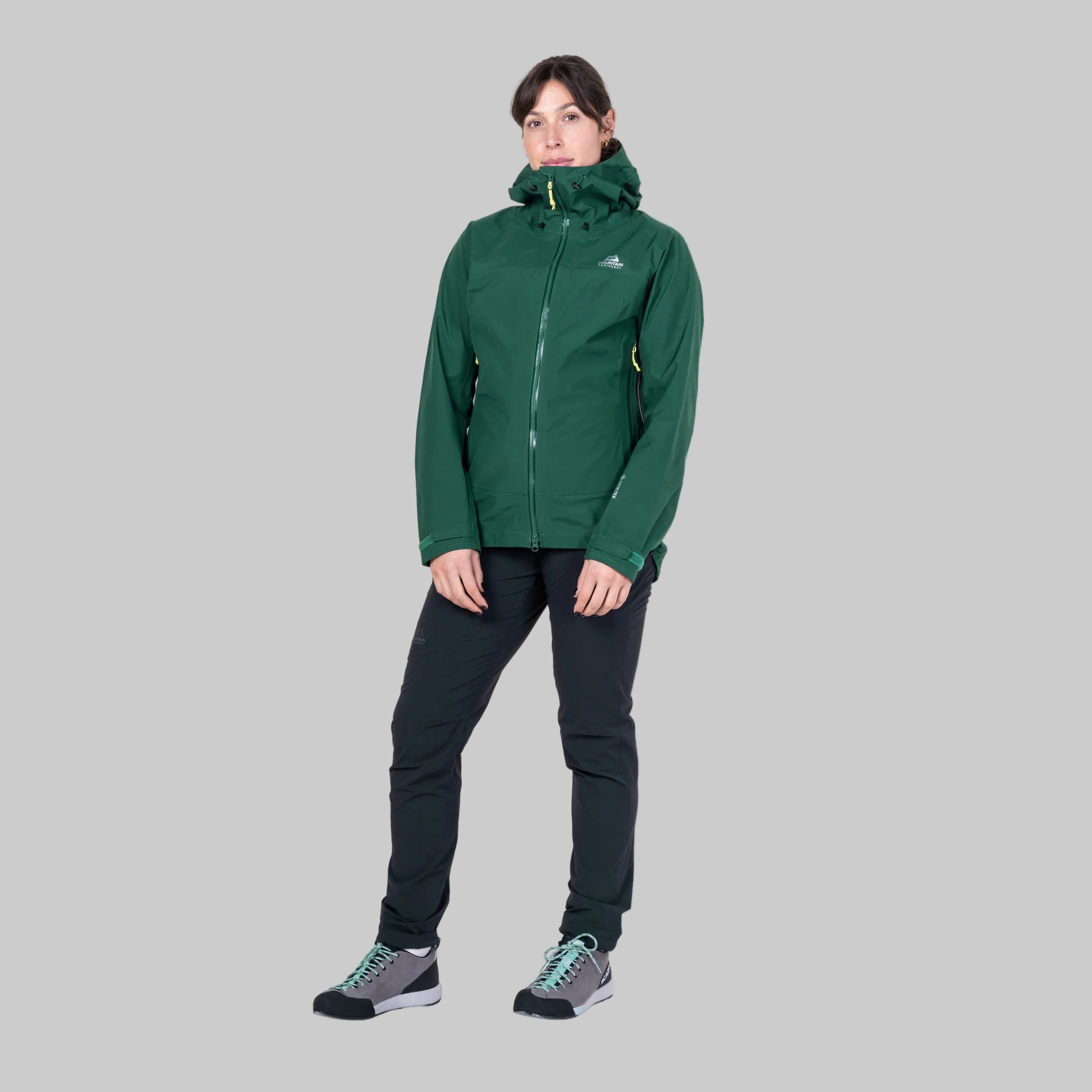 Person wearing a green jacket and black pants on a white background