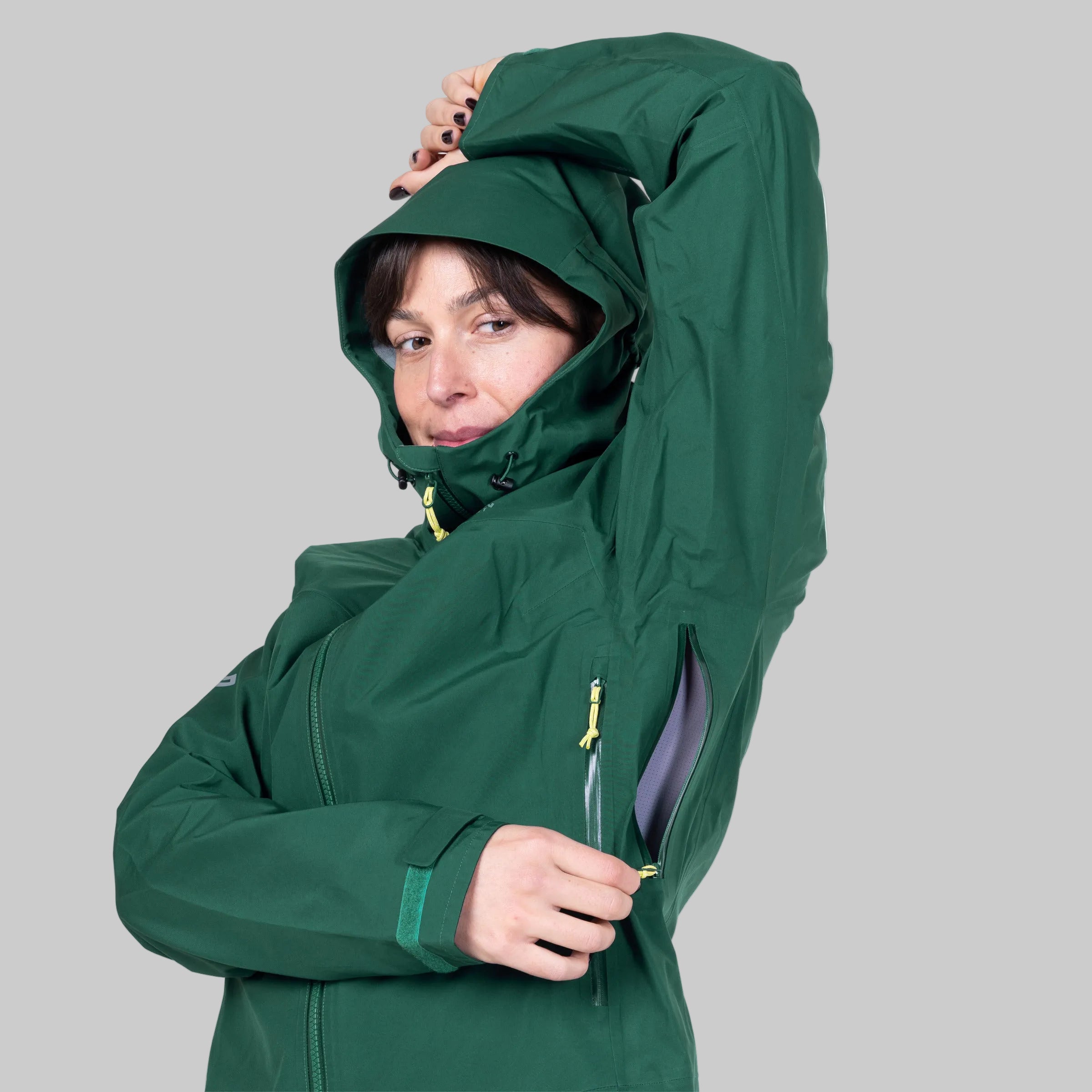 Person wearing a green jacket with the hood up on a white background