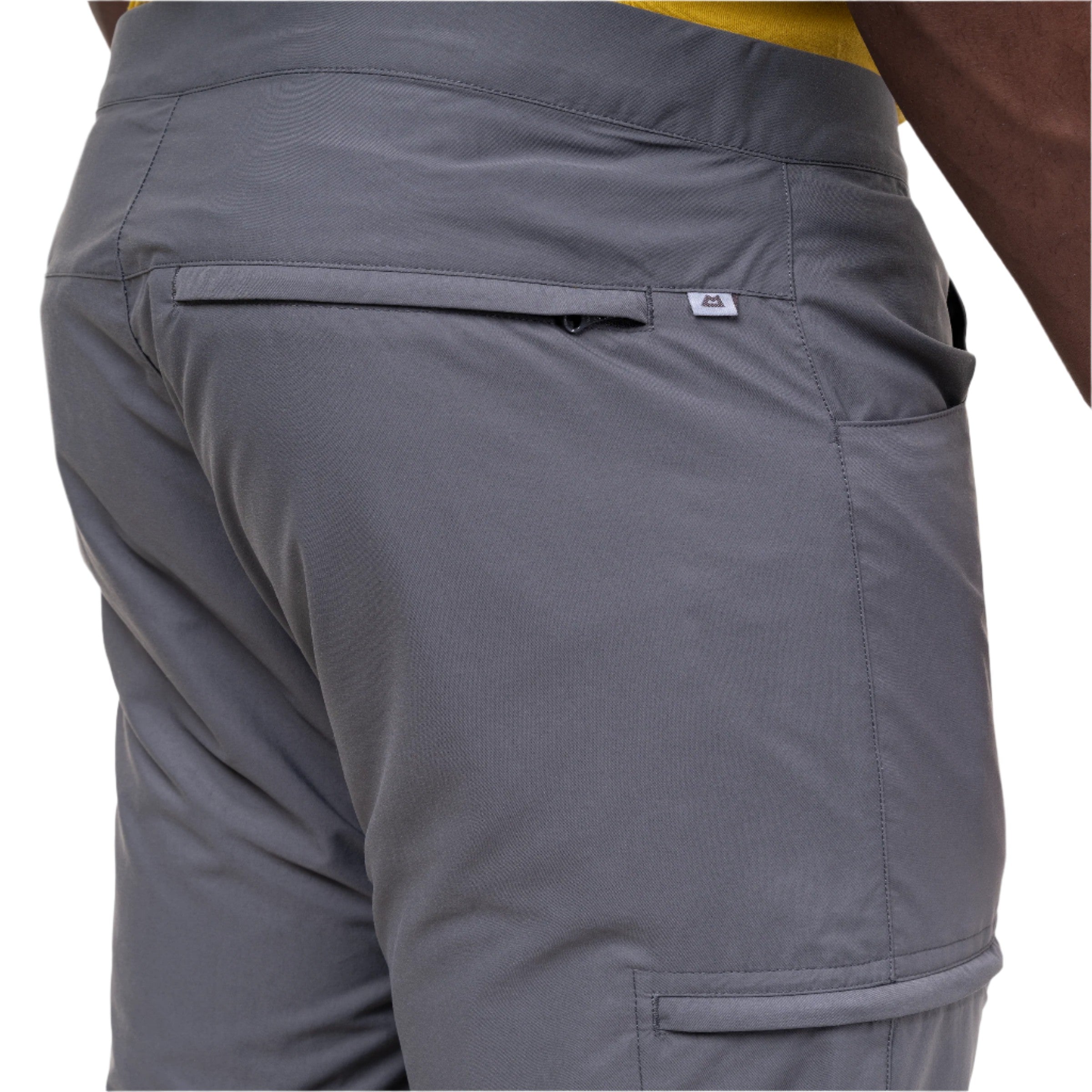 Close-up of the back waistband and pocket area of gray athletic shorts worn by a model, showing a small white logo tab on the pocket.