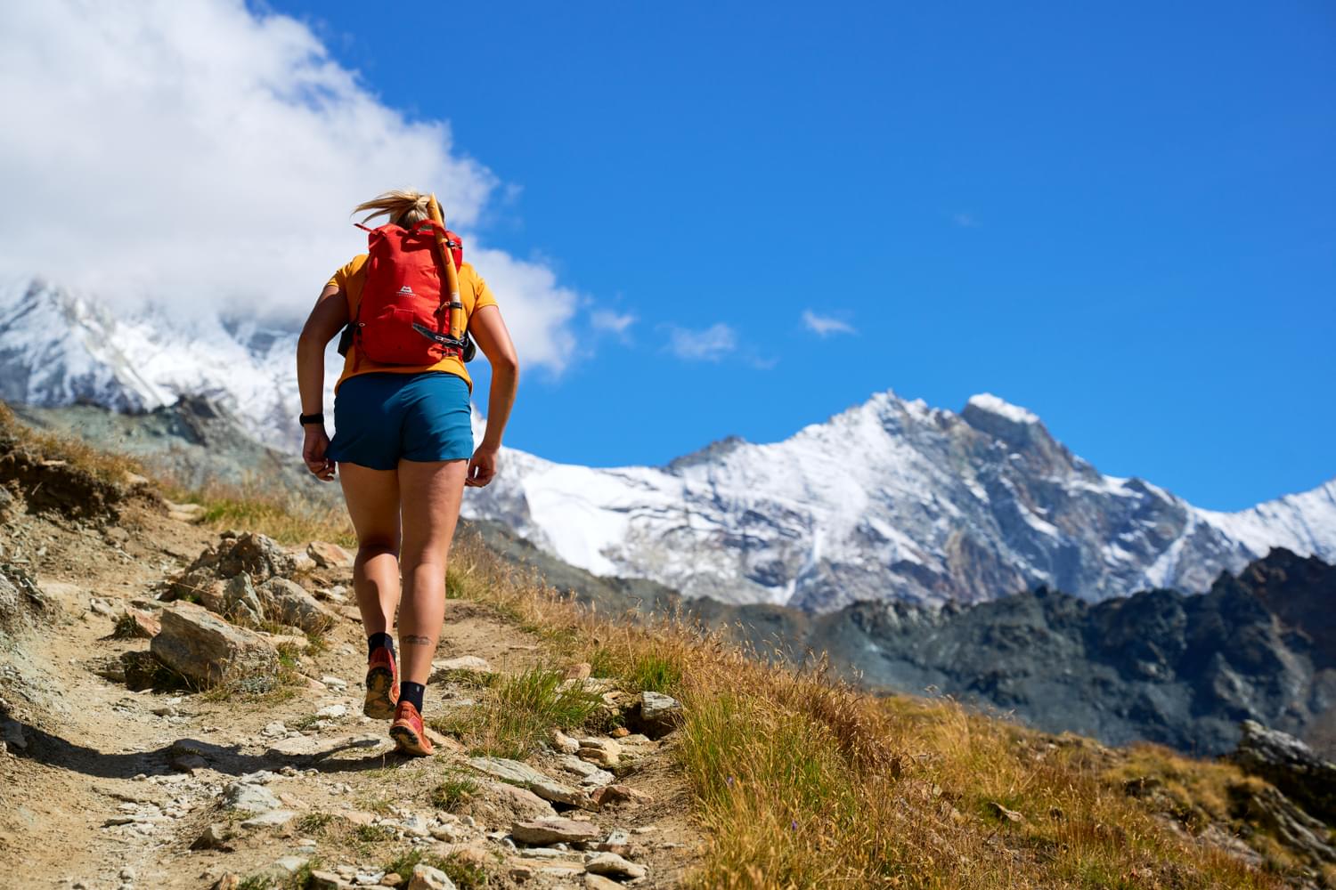 Image of a female hiker walking up hill in the sun 