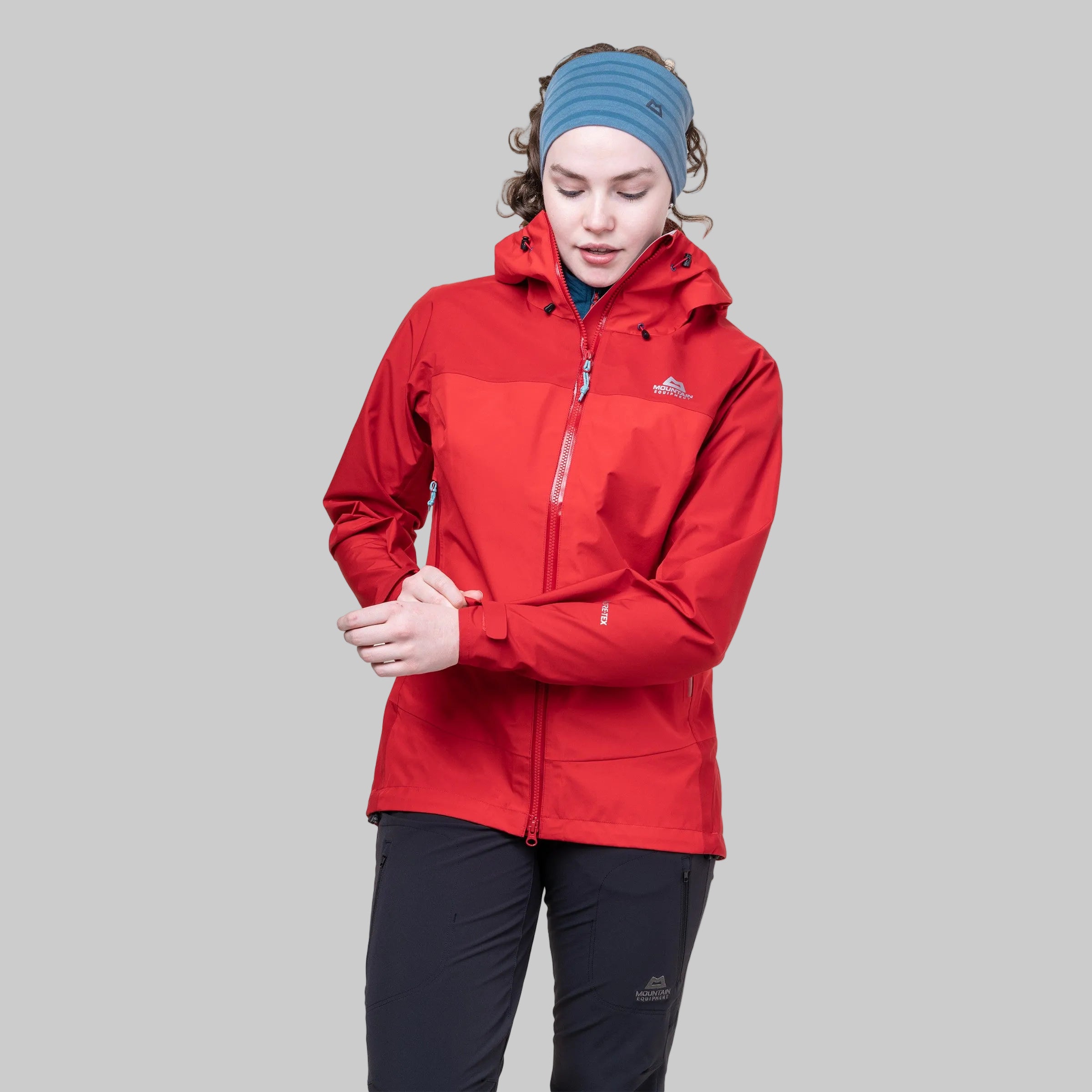 Model wearing a red waterproof jacket with a mountain equipment brand logo on a white background