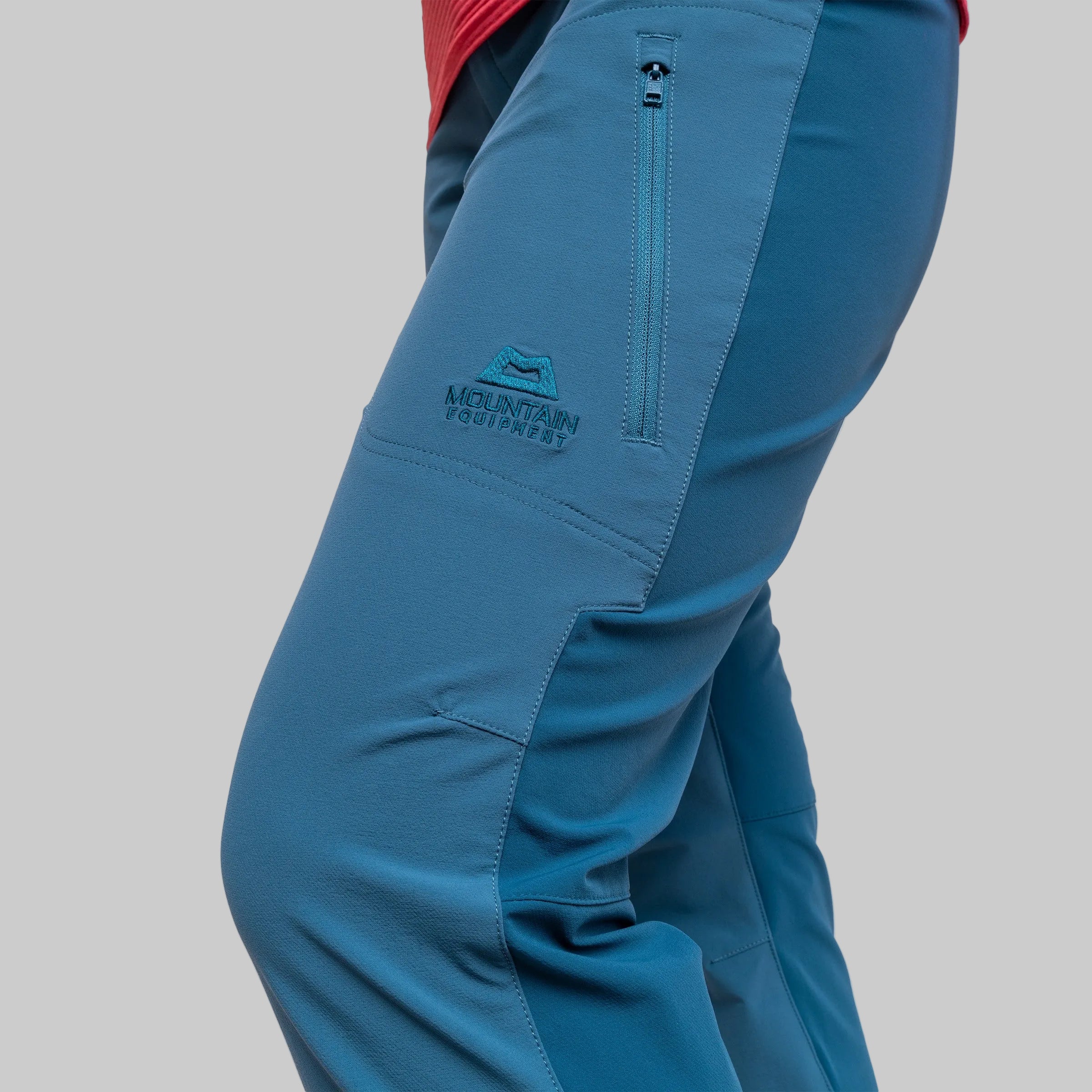 wearing a teal colour mountain equipment branded pant on a gray background
