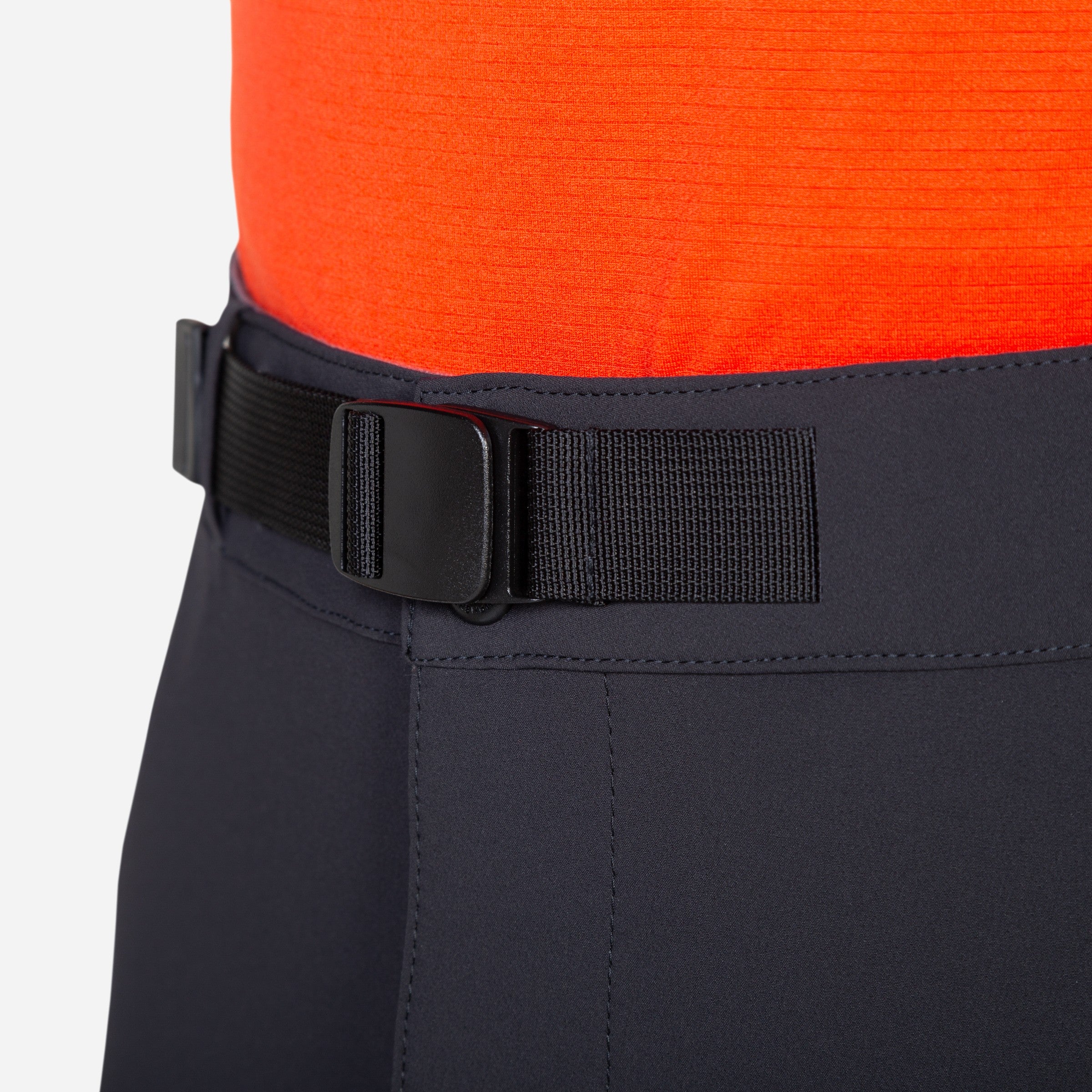 Close-up of black pants with a belt and bright orange shirt on a white background
